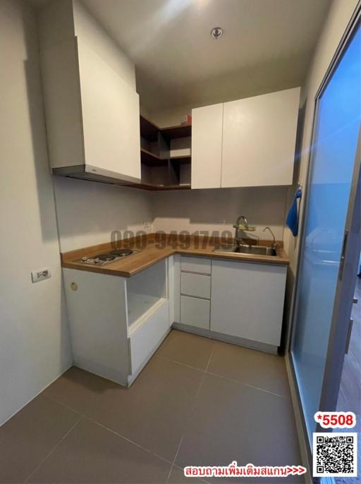 Compact kitchen with wooden countertops and white cabinetry