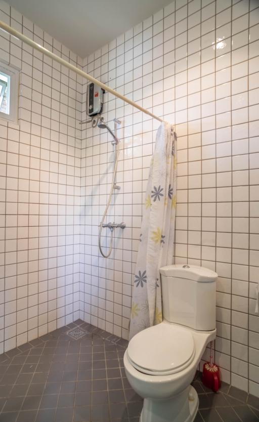 White tiled bathroom with an electric shower and toilet