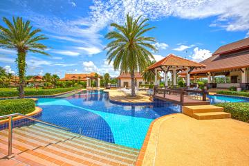 Bright and inviting community pool area with lush palm trees and gazebos