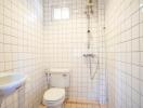 Bright bathroom with white tiles, shower and toilet facilities