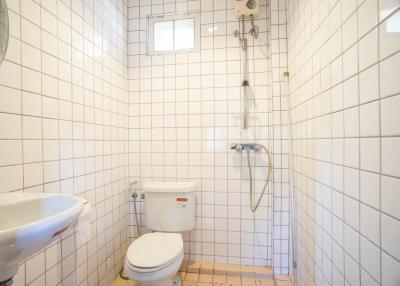 Bright bathroom with white tiles, shower and toilet facilities