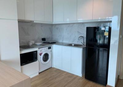 Modern kitchen with white cabinetry, washing machine, and fridge