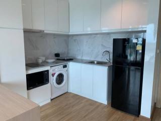 Modern kitchen with white cabinetry, washing machine, and fridge