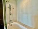 Clean bathroom with white tiles and fitted bathtub with shower