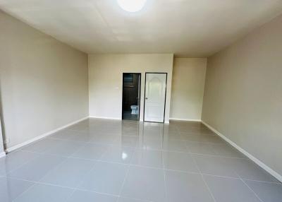 Spacious unfurnished room with glossy tiled flooring and a glass door