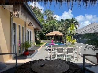 Spacious outdoor patio with swimming pool, dining area, and lush greenery