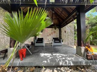 Spacious outdoor living area with tropical vibe, comfortable seating and natural shade