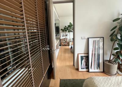 Cozy bedroom with wooden blinds, green accent rug, and framed art leaning against the wall