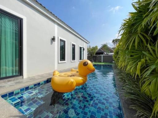 Cozy poolside area with a large inflatable duck and a view of a modern home exterior