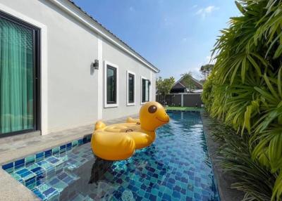 Cozy poolside area with a large inflatable duck and a view of a modern home exterior