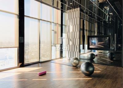 Modern living room with large windows, hardwood floors, and exercise equipment