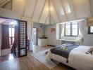 Spacious bedroom with vaulted ceiling, abundant natural light, and modern decor