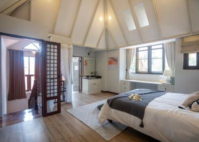 Spacious bedroom with vaulted ceiling, abundant natural light, and modern decor