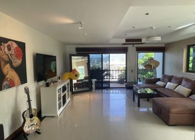 Spacious living room with modern furnishings, a large leather sofa, and glossy tiled flooring