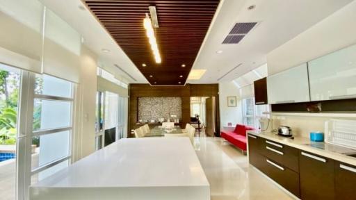 Modern kitchen with white countertops, red accents, and pool view