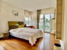 Bright and modern bedroom with wooden flooring and balcony access