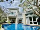 Spacious two-story house with a large swimming pool and lush garden