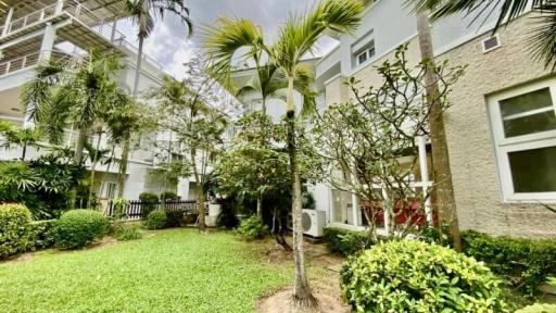 Lush green common space with tropical landscaping outside modern residential buildings