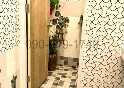 Bathroom with patterned wall and floor tiles, wooden door, and decorative elements