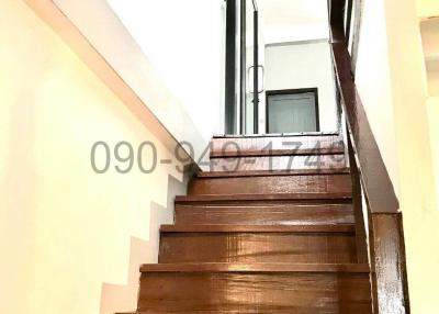 Wooden staircase leading to the upper floor with a black metal railing
