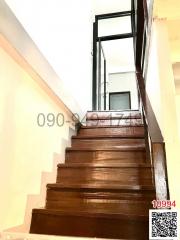 Wooden staircase leading to the upper floor with a black metal railing