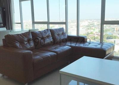 Spacious living area with leather sofa, large windows, and city view