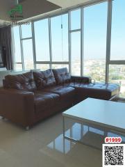 Spacious living area with leather sofa, large windows, and city view