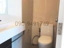 Modern bathroom with white and beige tiles featuring a sink, toilet, and shower