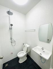 Compact modern bathroom with wall-mounted sink, toilet, and shower