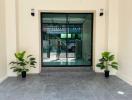 Spacious and well-lit entrance area with large glass doorway and potted plants