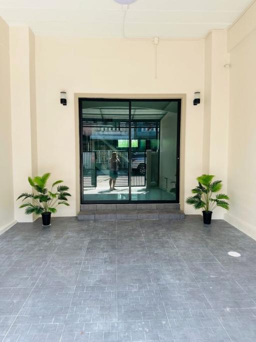 Spacious and well-lit entrance area with large glass doorway and potted plants