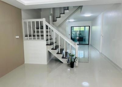Bright and spacious staircase area leading to upper floors with glossy tiled flooring