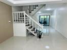 Bright and spacious staircase area leading to upper floors with glossy tiled flooring