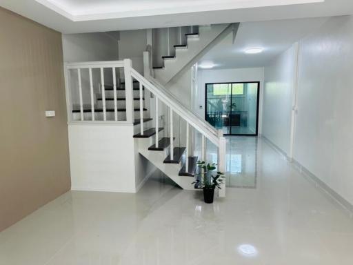 Bright and spacious staircase area leading to upper floors with glossy tiled flooring