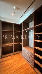 Spacious walk-in closet with built-in wooden shelves and drawers