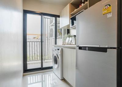 Compact laundry area with large window, washing machine, and modern refrigerator