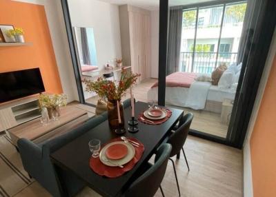 Modern dining area with an open layout towards the living space, featuring a black dining table, a large window, and hardwood flooring