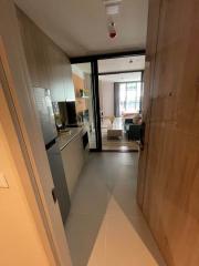 Modern apartment interior showing the entrance hall leading to living room with kitchen on the left