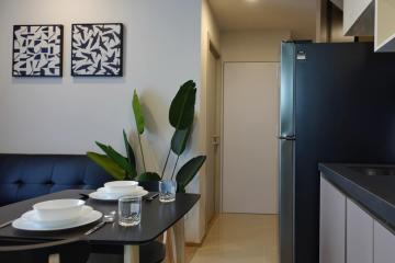 Modern kitchen with a dining area featuring a black refrigerator, a compact dining table, and decorative wall art