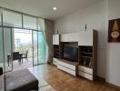 Spacious living room with natural light, balcony access, and modern furniture