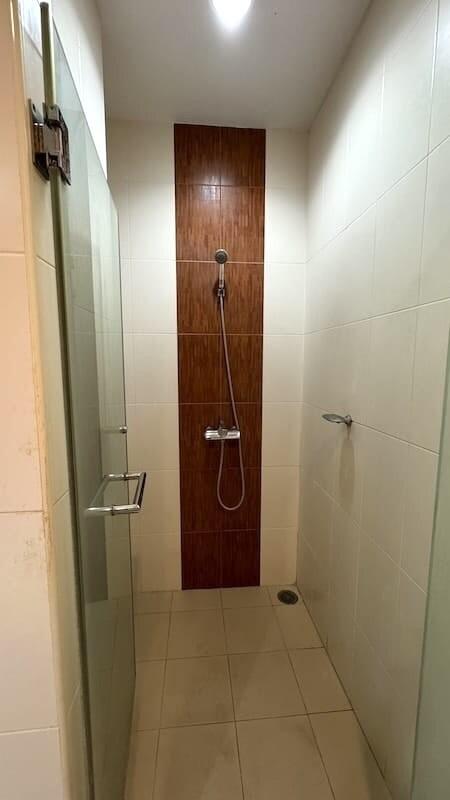 Compact tiled bathroom with shower and wooden door