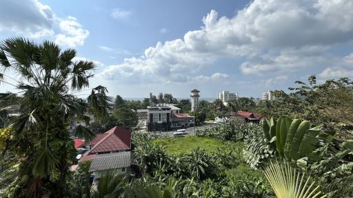 Panoramic view from a property showing a tropical landscape with diverse vegetation and urban skyline