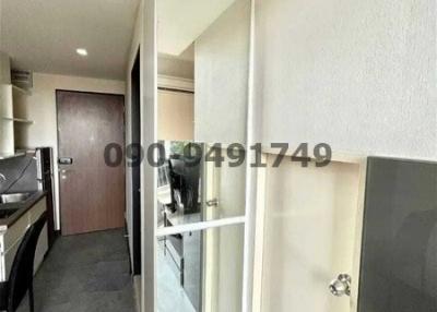 Compact modern hallway leading to a kitchen with open door and mirror reflection