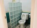 Compact bathroom with tiled flooring and privacy partition