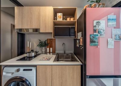 Modern compact kitchen with stainless steel appliances and pink refrigerator