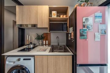 Modern compact kitchen with stainless steel appliances and pink refrigerator