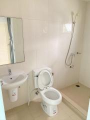 Clean white tiled bathroom with toilet and sink