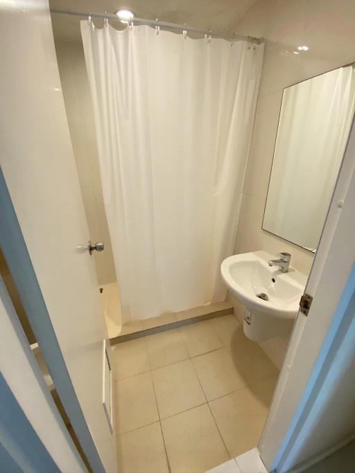 Small bathroom with white fittings, shower curtain, and mirror