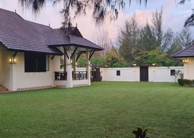 Spacious residential property with lush green lawn and traditional architecture