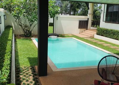 View of a backyard with a swimming pool and garden from a shaded patio